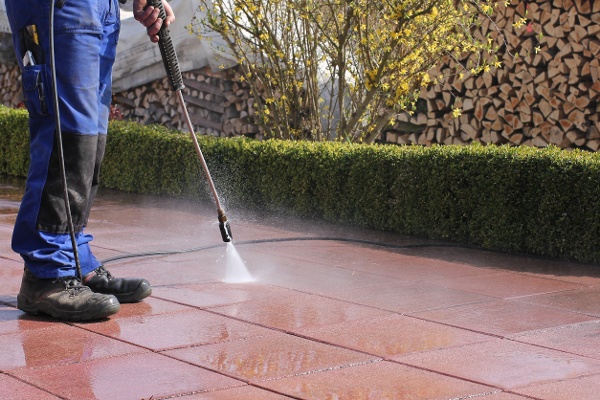 Bird control expert cleaning a building patio with water and bird control cleaning agent